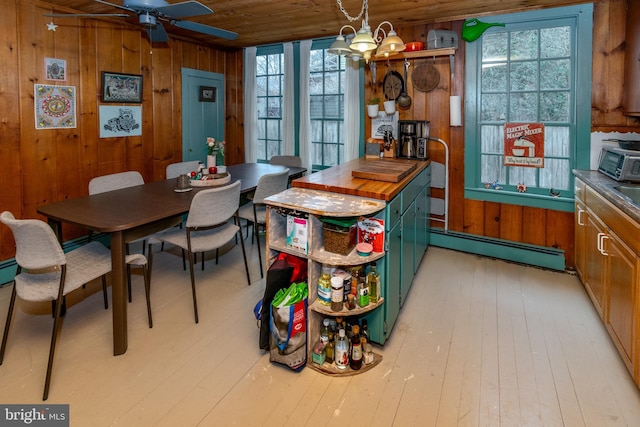 dining space with light wood-type flooring, baseboard heating, wood walls, and wooden ceiling