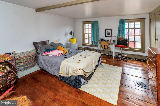 bedroom featuring beamed ceiling, multiple windows, a baseboard radiator, and hardwood / wood-style flooring