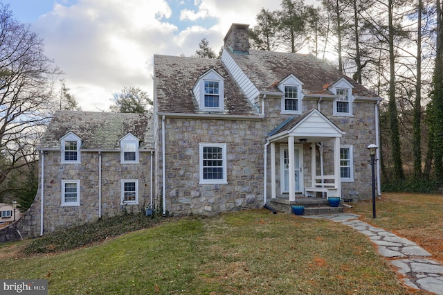 view of front of home with a front lawn, stone siding, and a chimney