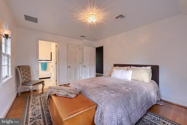 bedroom with baseboards, visible vents, and wood finished floors