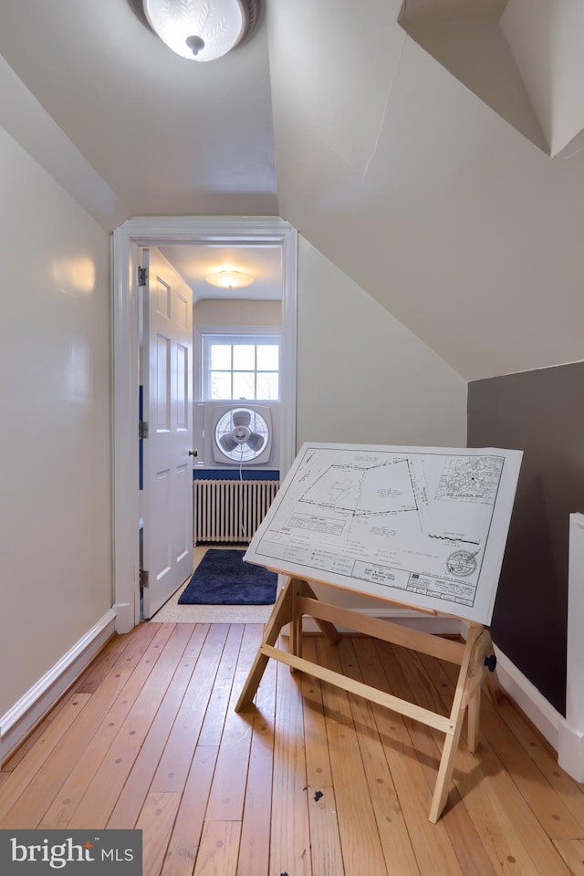 interior space featuring baseboards, radiator, wood finished floors, and lofted ceiling