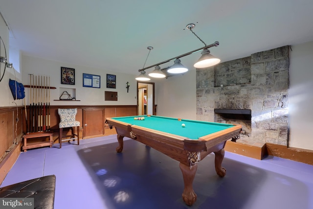 recreation room with a wainscoted wall, a fireplace, concrete floors, and billiards