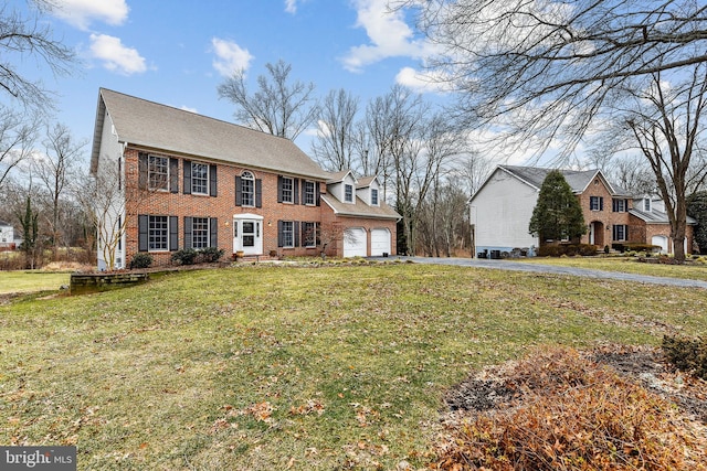 view of front of home featuring a garage, brick siding, a front yard, and aphalt driveway