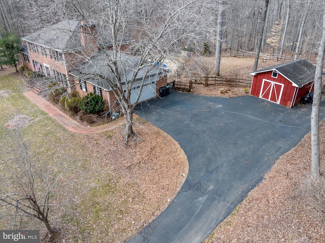 exterior space featuring a shed, an outdoor structure, fence, and aphalt driveway