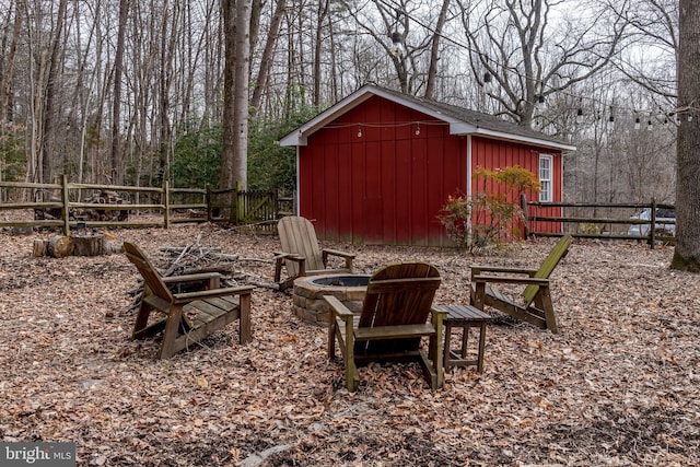 view of yard with a fire pit, a storage unit, an outbuilding, and fence