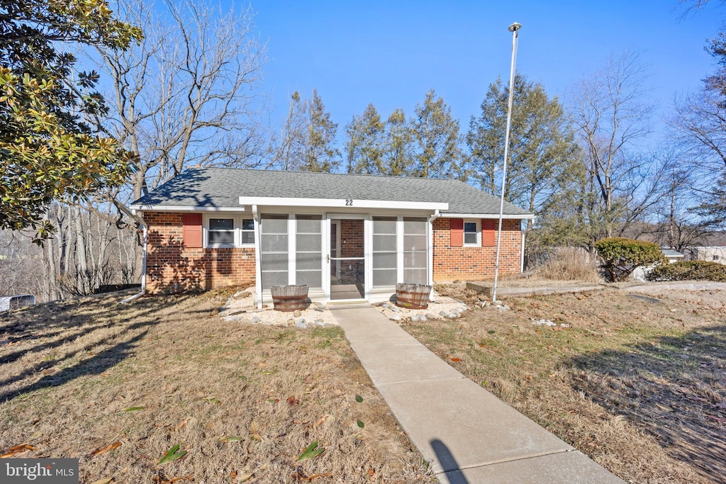 single story home featuring a front lawn and a sunroom