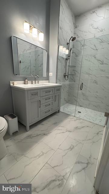 full bathroom featuring a marble finish shower, vanity, toilet, and marble finish floor