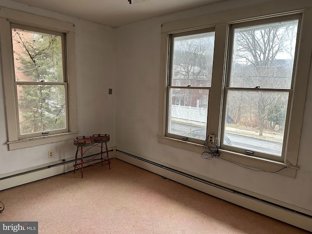 spare room featuring a baseboard heating unit and a healthy amount of sunlight