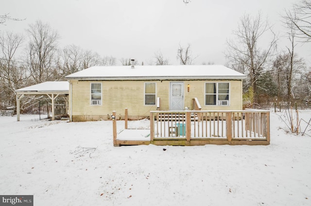 snow covered rear of property with a deck