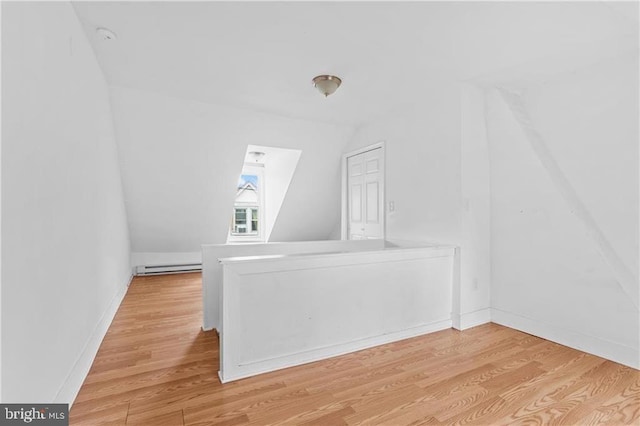 bonus room featuring lofted ceiling, a baseboard heating unit, light wood-type flooring, and baseboards