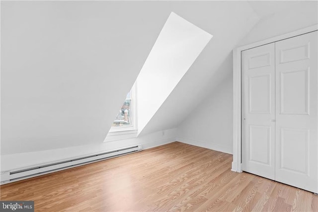 bonus room featuring a baseboard heating unit, light wood-style floors, and lofted ceiling with skylight