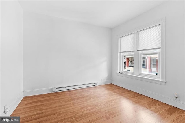 spare room with a baseboard radiator, light wood-style flooring, and baseboards