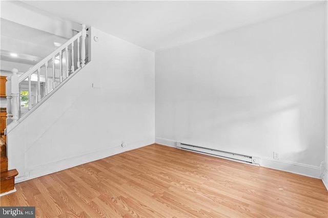 unfurnished living room featuring baseboards, a baseboard radiator, stairway, and wood finished floors