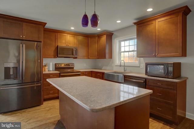 kitchen with stainless steel appliances, decorative light fixtures, light hardwood / wood-style floors, a center island, and sink