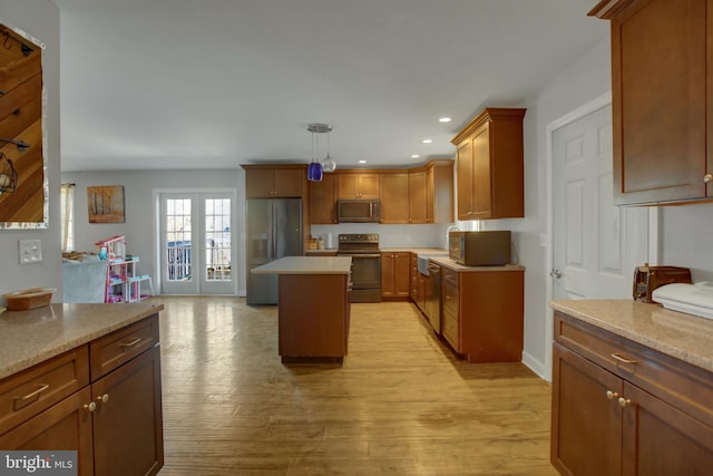 kitchen featuring light hardwood / wood-style flooring, stainless steel appliances, french doors, pendant lighting, and a center island