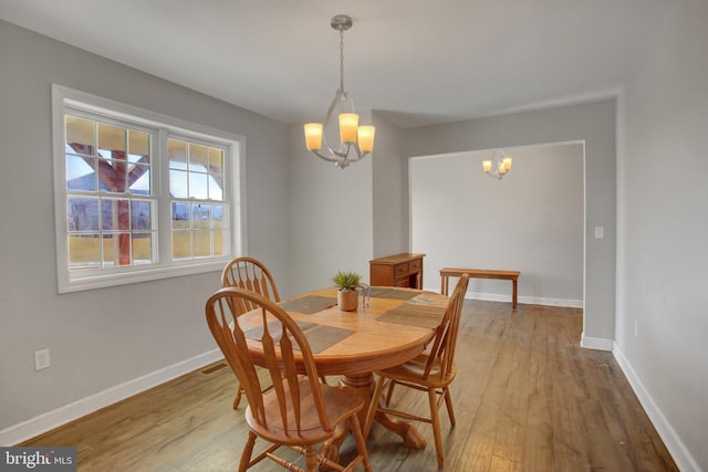 dining room with hardwood / wood-style floors and an inviting chandelier