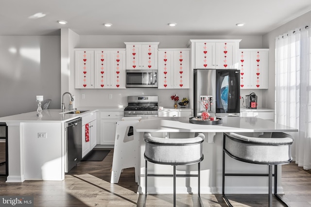 kitchen featuring appliances with stainless steel finishes, sink, a kitchen breakfast bar, dark hardwood / wood-style floors, and white cabinets