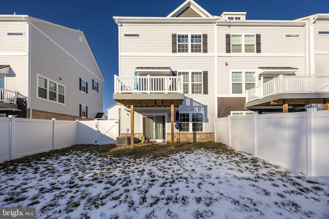 snow covered back of property featuring cooling unit and a wooden deck