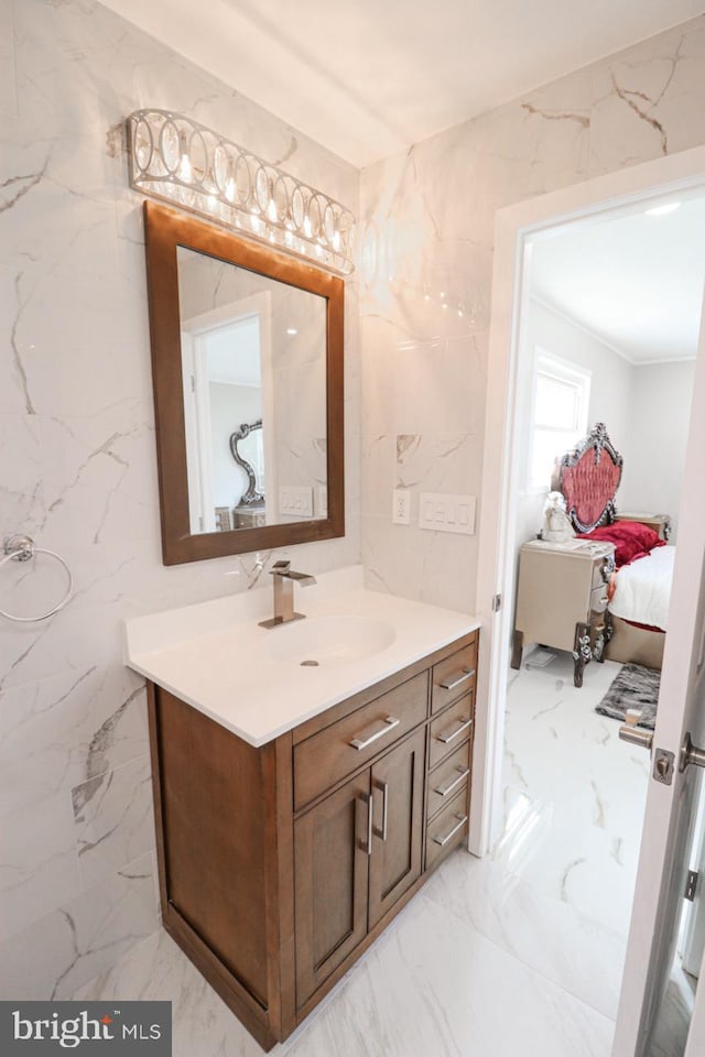 ensuite bathroom with marble finish floor, stone wall, connected bathroom, and vanity