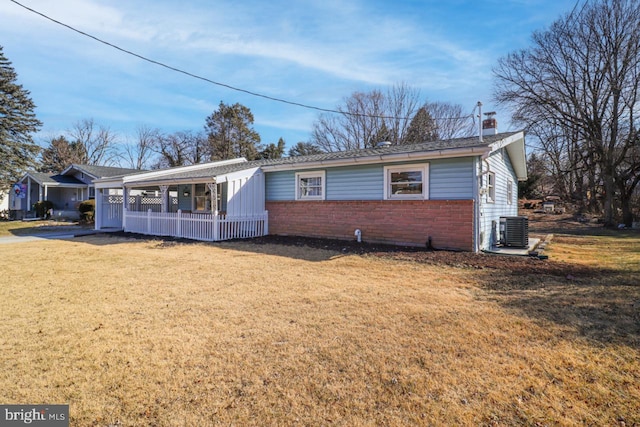 ranch-style home featuring central AC, a front lawn, a chimney, and brick siding