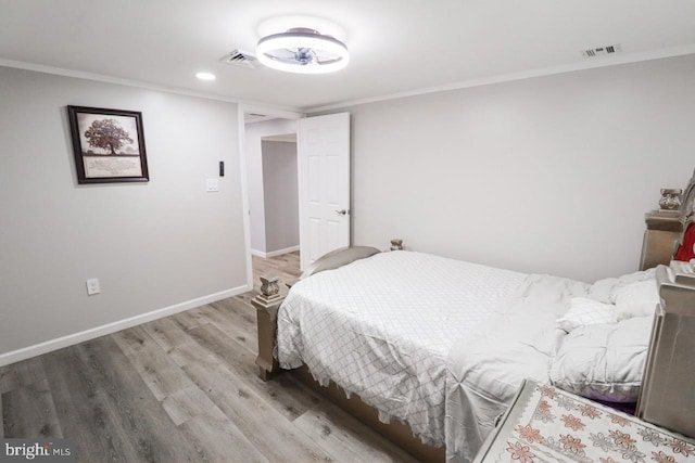 bedroom featuring baseboards, visible vents, wood finished floors, and ornamental molding