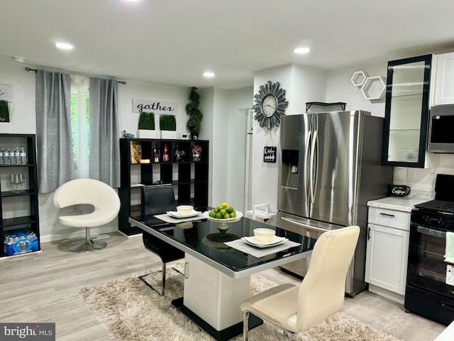 kitchen with white cabinets, light wood-type flooring, and appliances with stainless steel finishes