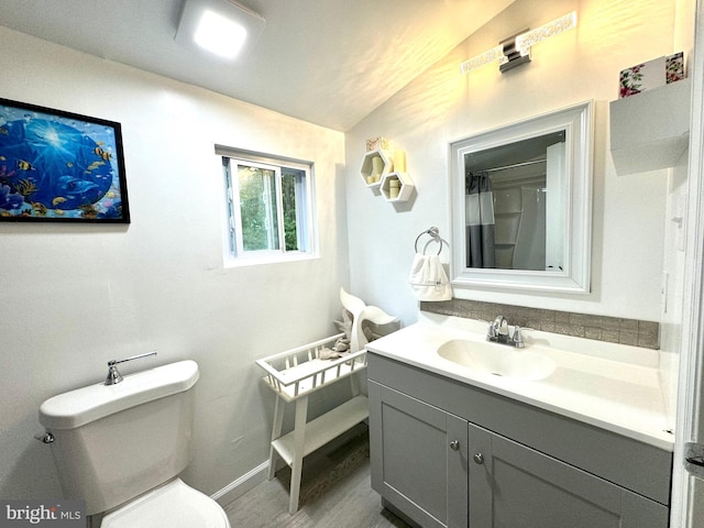 bathroom featuring lofted ceiling, vanity, walk in shower, toilet, and hardwood / wood-style flooring