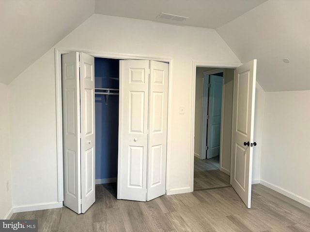 unfurnished bedroom featuring a closet, lofted ceiling, and light hardwood / wood-style flooring