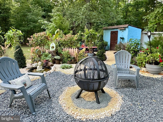 view of patio with an outdoor fire pit and a storage unit