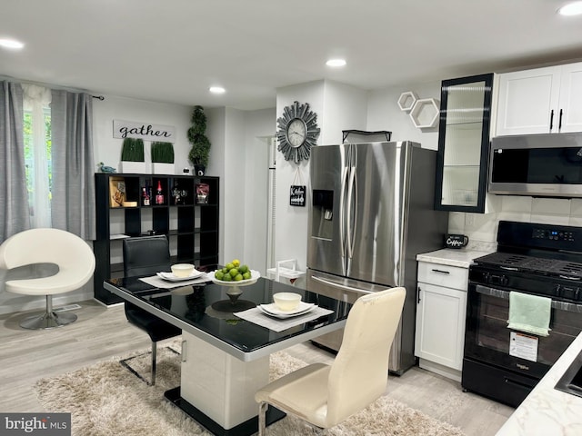 kitchen featuring white cabinets, light hardwood / wood-style floors, stainless steel appliances, and light stone counters