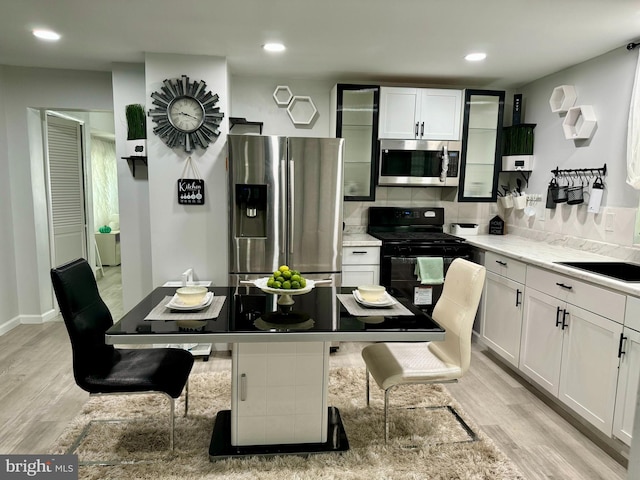 kitchen with appliances with stainless steel finishes, light hardwood / wood-style floors, white cabinetry, and a breakfast bar area