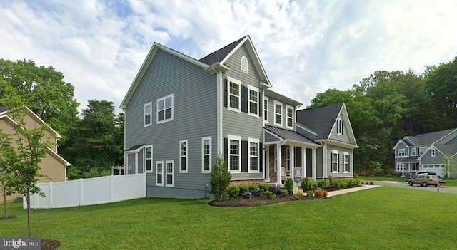 view of front of home featuring a standing seam roof, fence, and a front lawn