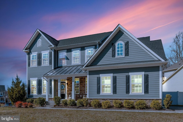 view of front of home with a standing seam roof, stone siding, metal roof, and a porch