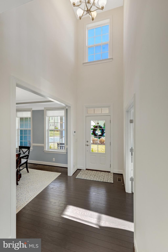 foyer with an inviting chandelier, a high ceiling, baseboards, and dark wood finished floors