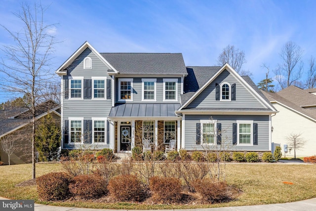 view of front of home featuring metal roof, a standing seam roof, a front yard, and roof with shingles