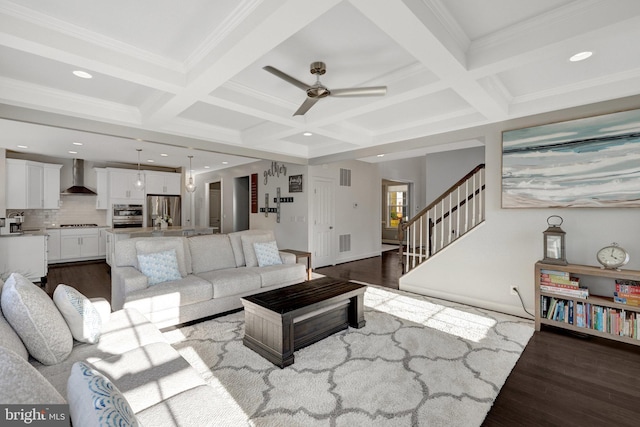 living room featuring dark wood-type flooring, beam ceiling, and stairway