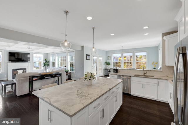 kitchen featuring stainless steel appliances, dark wood-type flooring, a sink, and light stone counters