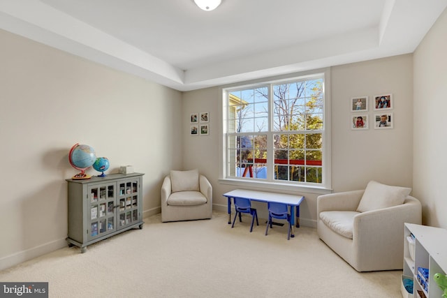 sitting room featuring a tray ceiling, carpet flooring, and baseboards