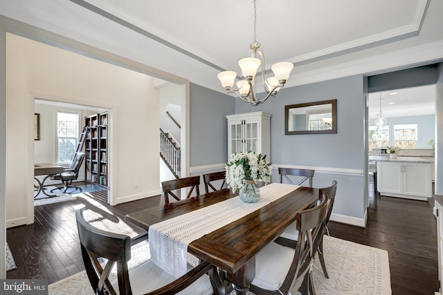 dining room featuring dark wood-style floors, a tray ceiling, a chandelier, and a healthy amount of sunlight