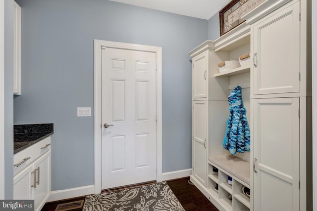 mudroom featuring dark wood-type flooring, visible vents, and baseboards