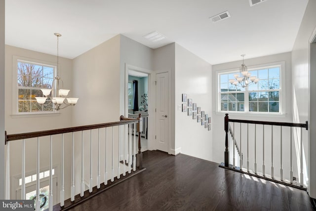 hallway with a chandelier, visible vents, an upstairs landing, and dark wood-style floors