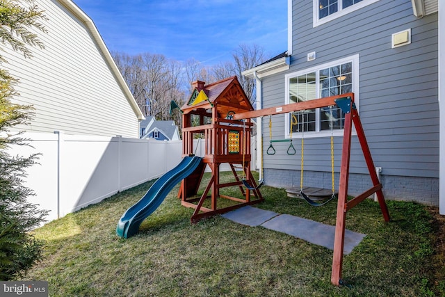 view of playground with fence and a lawn