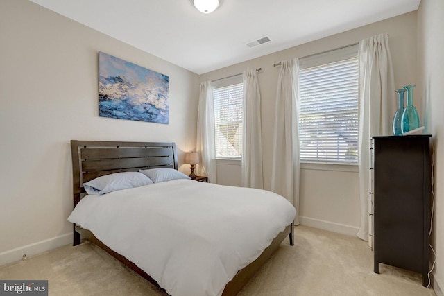 bedroom with baseboards, visible vents, and light colored carpet