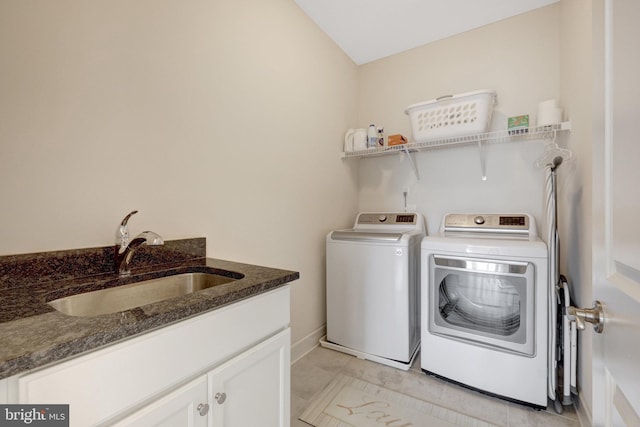 washroom with cabinet space, a sink, washing machine and clothes dryer, and light tile patterned flooring