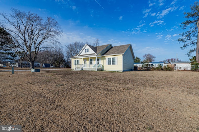 view of front of home with a shingled roof, a front yard, and covered porch