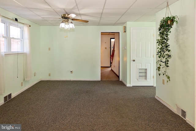 empty room with dark carpet, ceiling fan, and a paneled ceiling