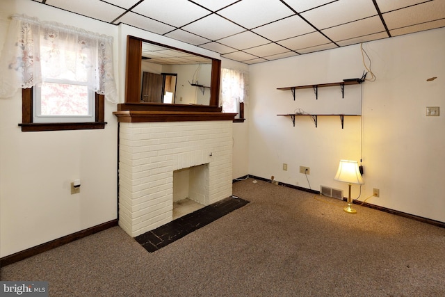 unfurnished living room featuring dark colored carpet, a paneled ceiling, and a fireplace