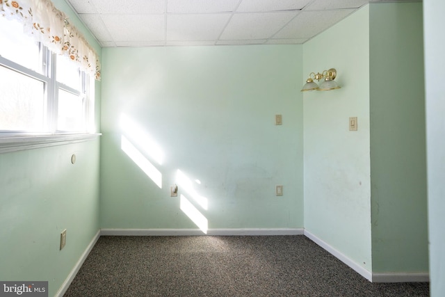 carpeted empty room with a drop ceiling