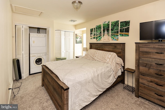 bedroom with stacked washing maching and dryer, two closets, and light carpet