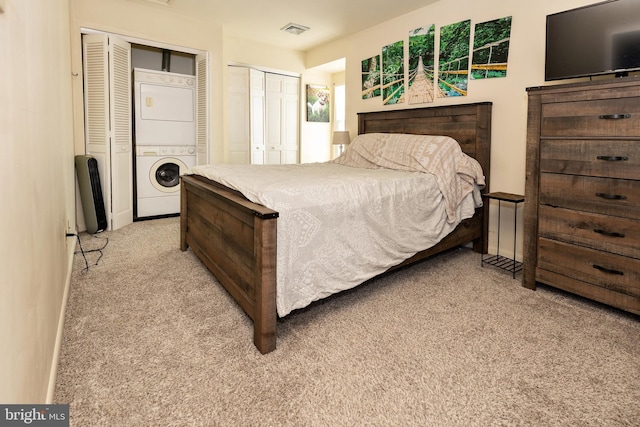 bedroom with stacked washer and dryer, light colored carpet, and two closets